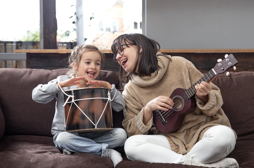 Mom plays with her daughter at home. Lessons on a musical instrument. Children's development and family values. The concept of children's friendship and family.