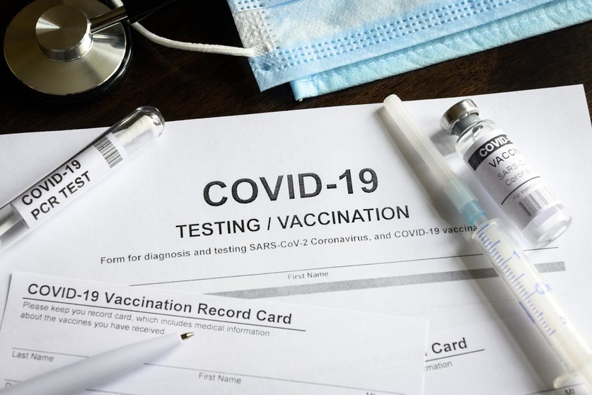 COVID-19 testing and vaccination medical form on desk, coronavirus vaccine injection kit and vaccination certificate on desk. Concept of corona virus diagnosis, vaccine, health and immunization.