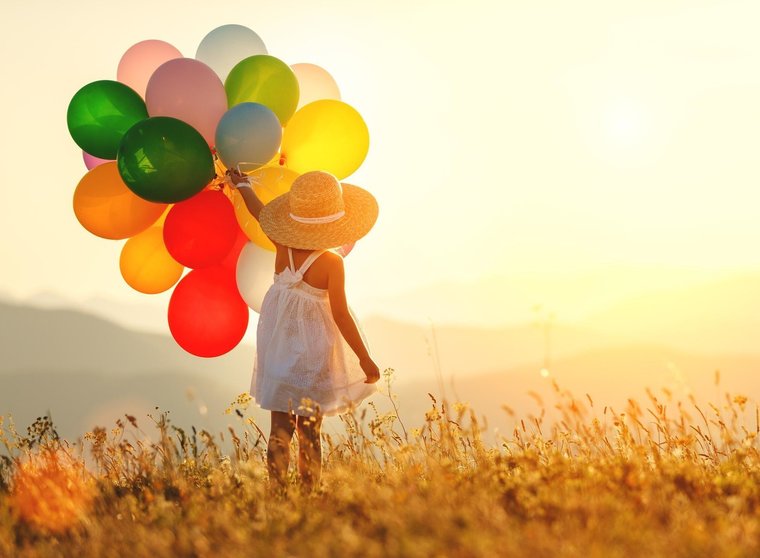young happy child girl with balloons at sunset in summer
